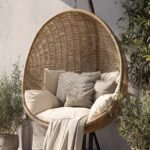 Close-up of the hanging egg chair with stand showing PE rattan weave and cushions